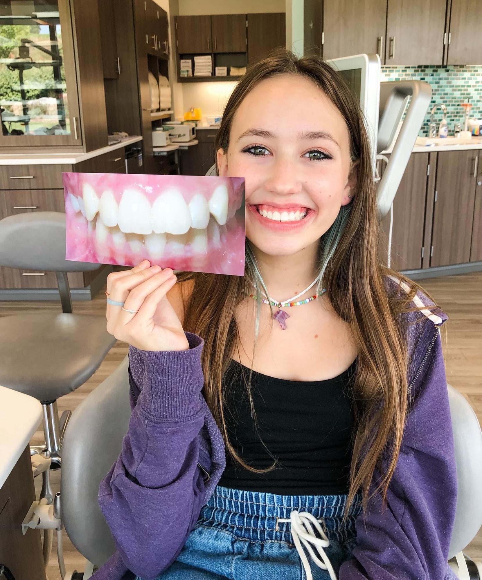 braces-omaha-ne-smiling-patient-holding-straight-teeth-photo Smiling patient holding a photo of straight teeth after braces treatment in Omaha, NE